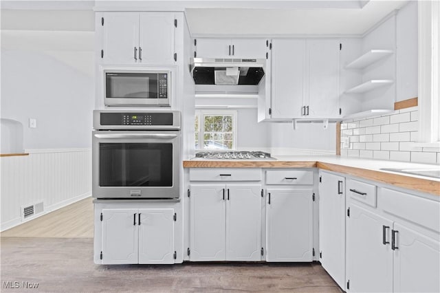 kitchen featuring visible vents, open shelves, white cabinets, light wood-style flooring, and stainless steel appliances