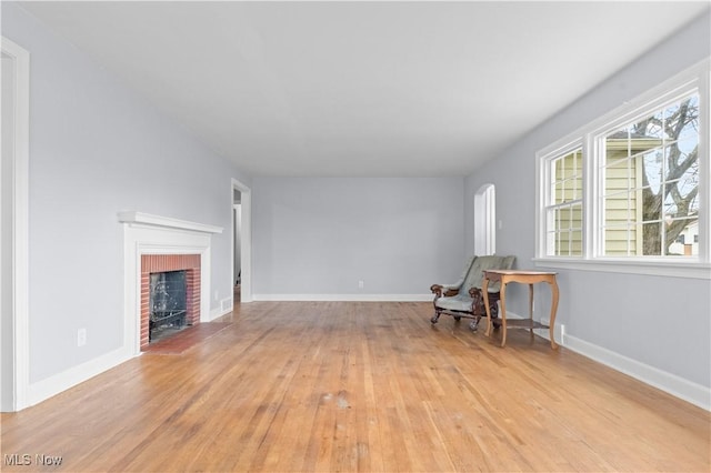 unfurnished living room featuring a fireplace, baseboards, and light wood-type flooring
