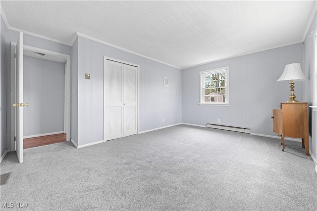 unfurnished bedroom with crown molding, a closet, baseboards, a baseboard heating unit, and carpet flooring