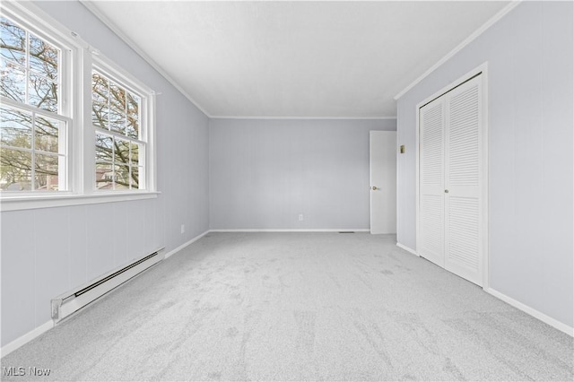 unfurnished bedroom featuring crown molding, carpet floors, baseboards, a baseboard radiator, and a closet