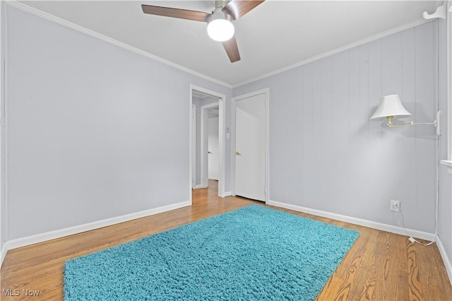empty room with baseboards, crown molding, ceiling fan, and wood finished floors
