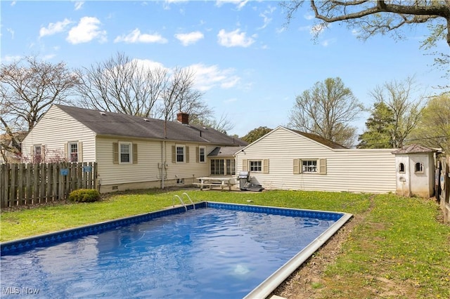 view of swimming pool with fence, an outbuilding, a fenced in pool, and a yard