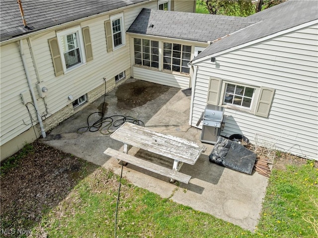 rear view of house featuring a shingled roof and a patio area