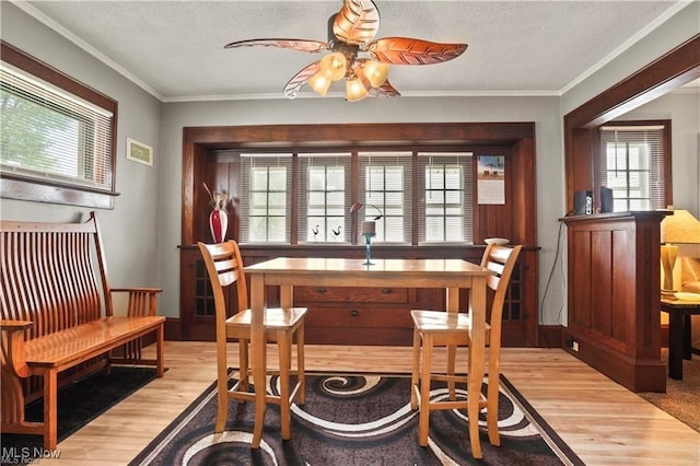 dining space with crown molding, ceiling fan, light wood-style flooring, and a textured ceiling