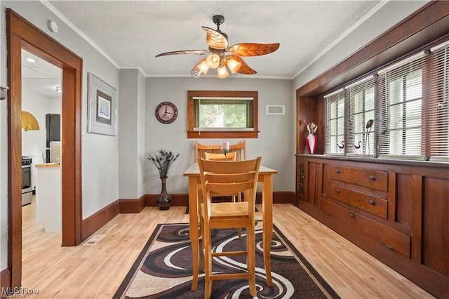 dining space featuring ceiling fan, a textured ceiling, crown molding, light wood-type flooring, and baseboards