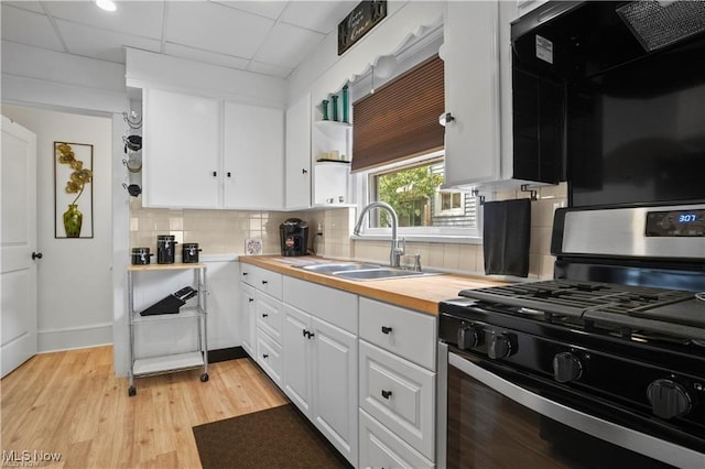 kitchen with a sink, decorative backsplash, white cabinetry, and gas range