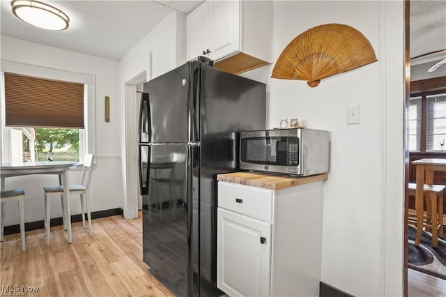 kitchen with plenty of natural light, freestanding refrigerator, stainless steel microwave, and light wood-type flooring