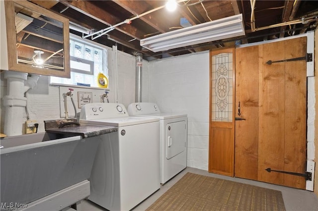 clothes washing area with laundry area, a sink, and washer and clothes dryer