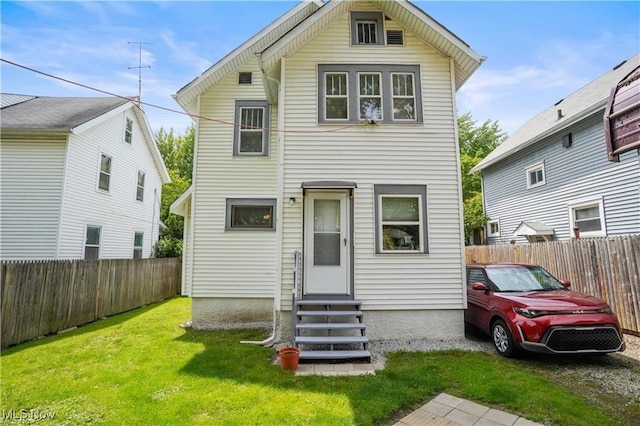 view of front of property with entry steps, a fenced backyard, and a front lawn