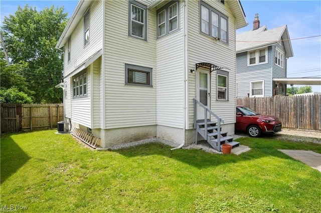 rear view of house with a lawn, a fenced backyard, and entry steps