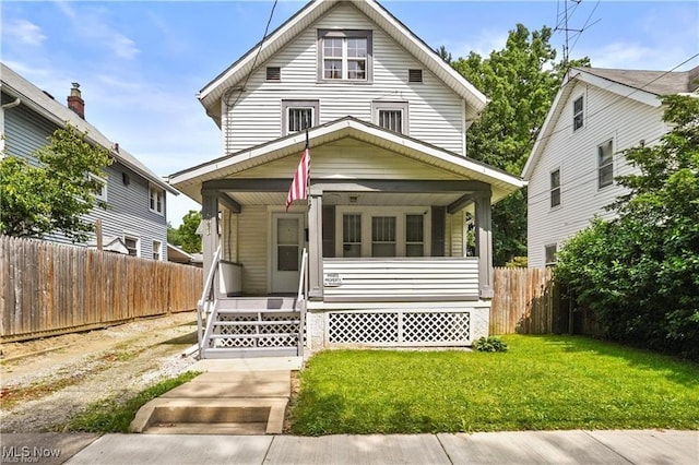 view of front of house featuring fence, covered porch, and a front yard
