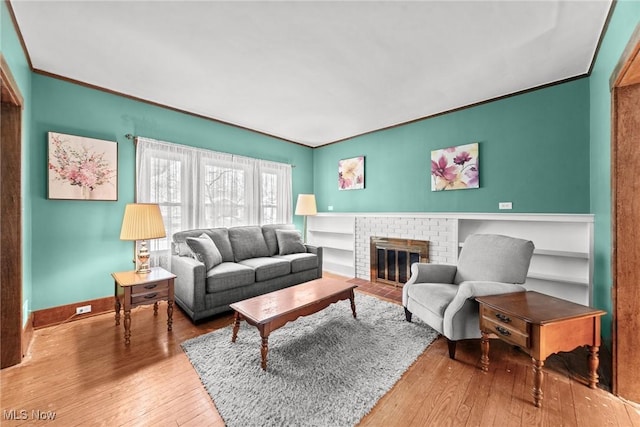 living area with baseboards, a fireplace, and hardwood / wood-style flooring