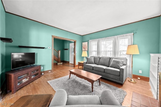 living area featuring stairs, baseboards, ornamental molding, and wood finished floors