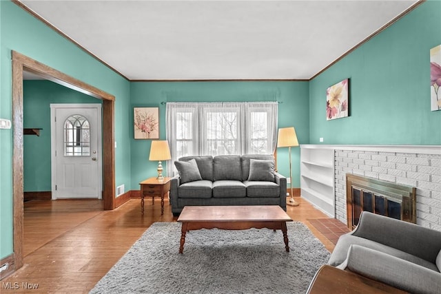 living room featuring crown molding, baseboards, visible vents, and a fireplace