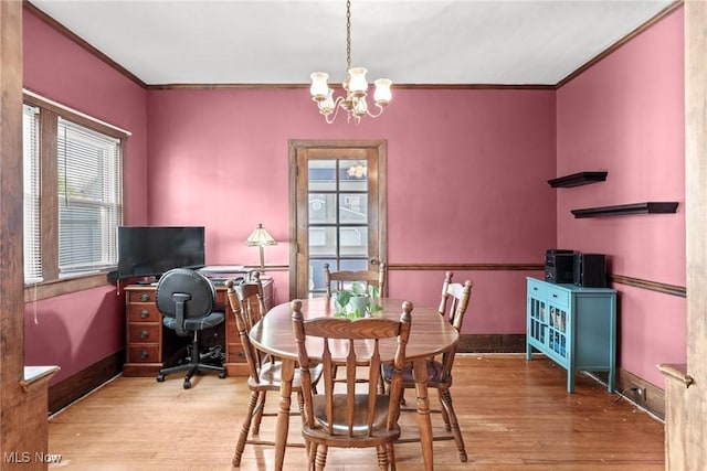 dining space with crown molding, baseboards, an inviting chandelier, and wood finished floors