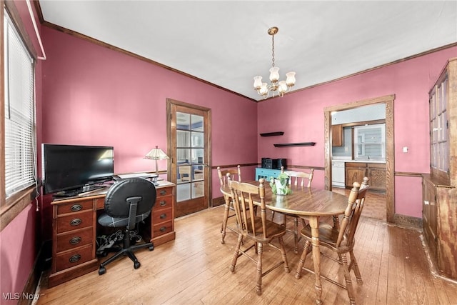dining room with wood-type flooring, ornamental molding, wainscoting, and a notable chandelier