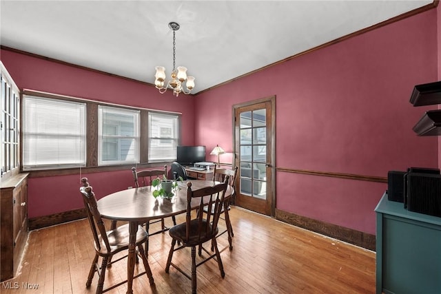 dining room with baseboards, ornamental molding, hardwood / wood-style floors, and a notable chandelier