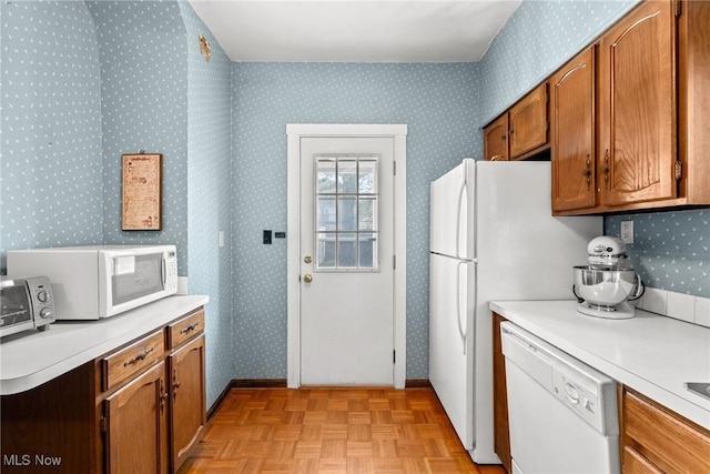 kitchen featuring white appliances, wallpapered walls, brown cabinetry, and light countertops