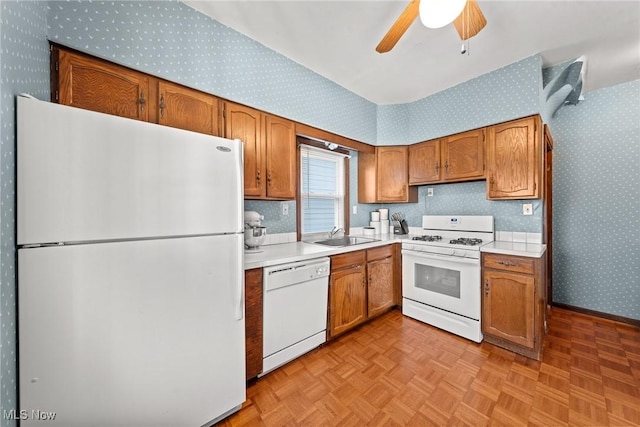 kitchen featuring ceiling fan, a sink, white appliances, light countertops, and wallpapered walls