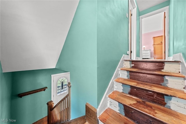 staircase with wood finished floors and lofted ceiling