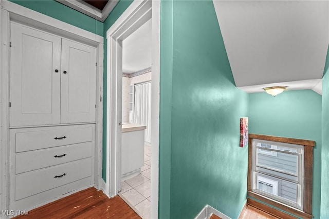 hall with baseboards, wood finished floors, and lofted ceiling