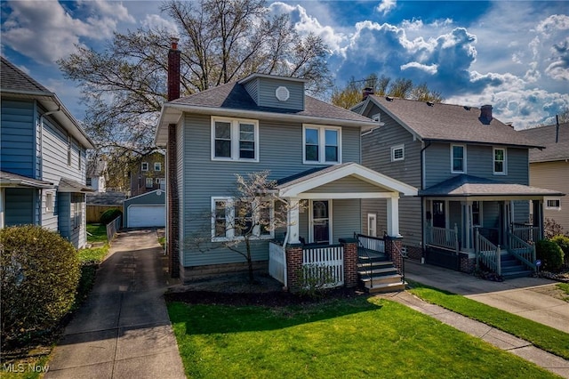 american foursquare style home with an outdoor structure, a garage, a front lawn, a chimney, and a porch