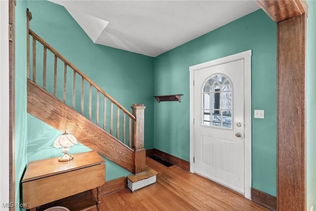 foyer entrance featuring baseboards, wood finished floors, and stairway