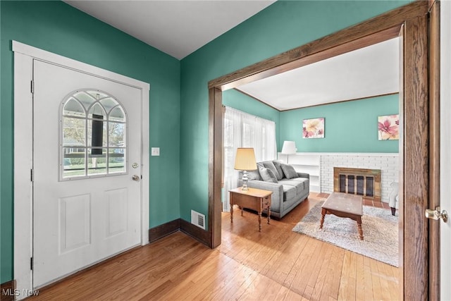 foyer entrance with visible vents, baseboards, a fireplace, and hardwood / wood-style flooring
