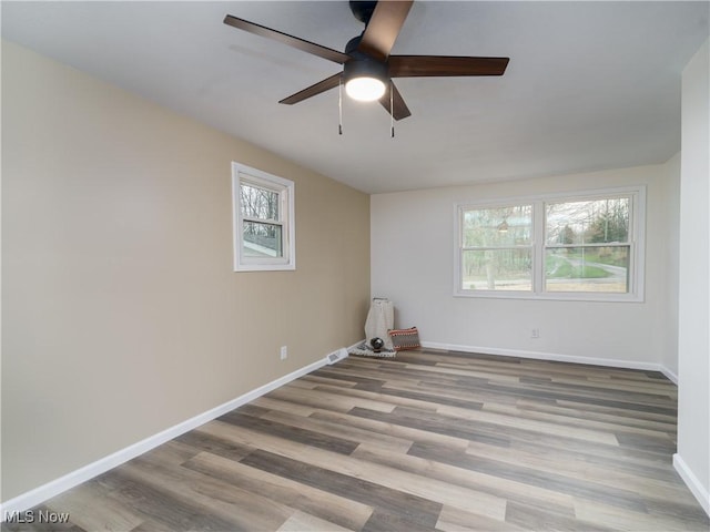 spare room featuring ceiling fan, baseboards, and wood finished floors