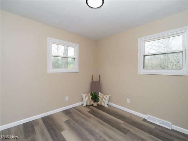 spare room with visible vents, baseboards, and wood finished floors