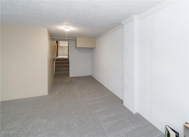 finished below grade area featuring stairway, carpet flooring, and a textured ceiling