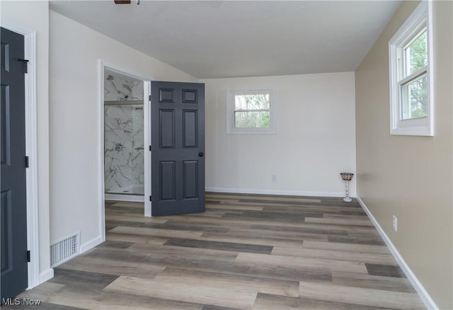 unfurnished bedroom featuring visible vents, baseboards, ensuite bathroom, and wood finished floors