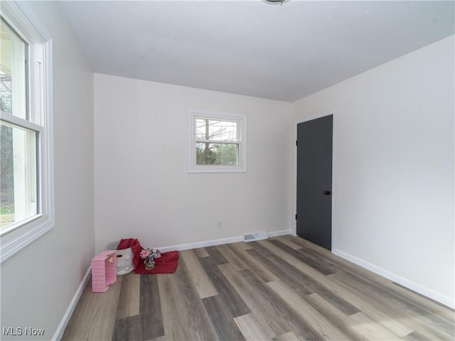 unfurnished room featuring visible vents, baseboards, and wood finished floors