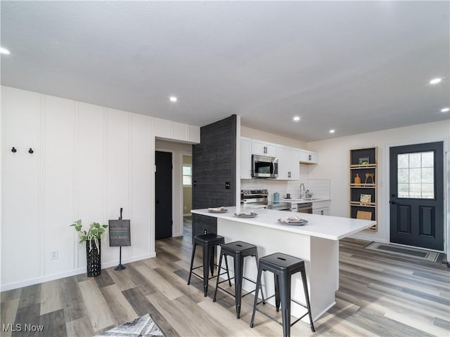 kitchen with plenty of natural light, appliances with stainless steel finishes, a breakfast bar, and light wood-type flooring