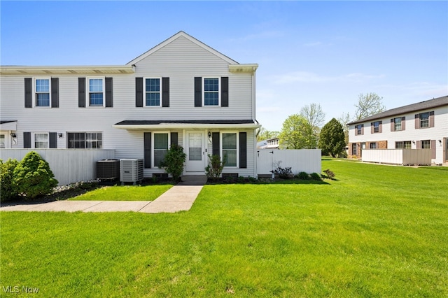 view of front of house featuring central air condition unit, fence, and a front lawn