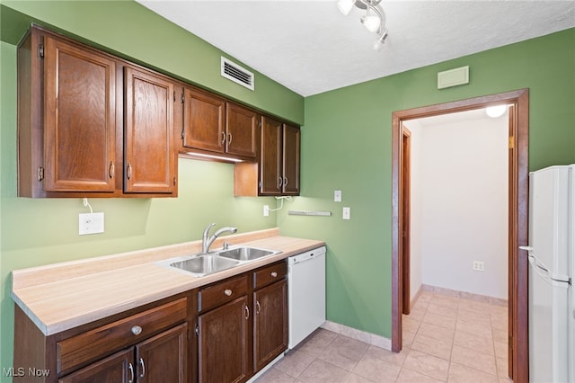 kitchen with visible vents, a sink, light countertops, light tile patterned floors, and white appliances