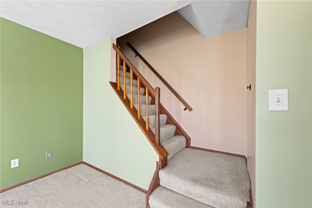 stairs featuring carpet flooring, a textured ceiling, and baseboards