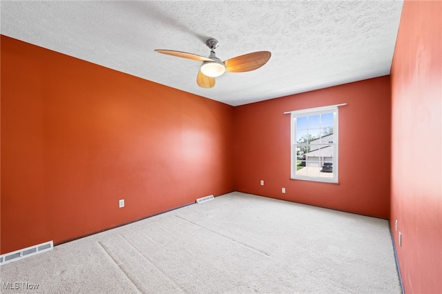 carpeted spare room with a textured ceiling, ceiling fan, and visible vents