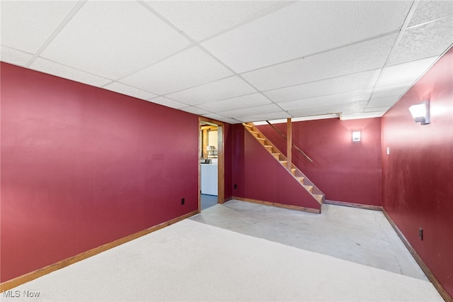 finished basement featuring baseboards, a drop ceiling, and stairway