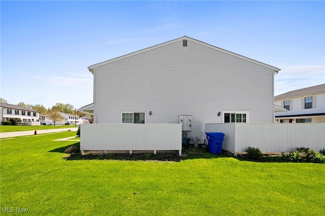 back of property featuring a lawn and fence