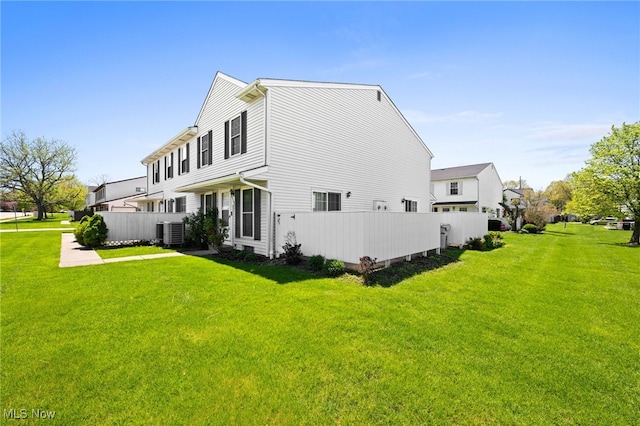 view of side of home with a lawn, fence, and cooling unit