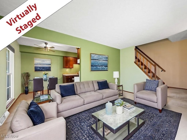 living room with a ceiling fan, visible vents, and stairway