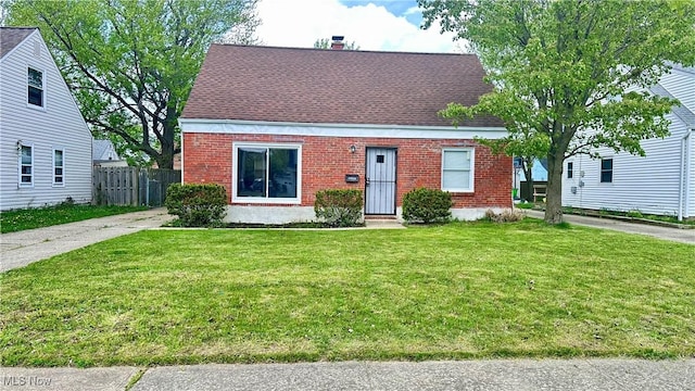 cape cod house featuring brick siding, fence, and a front yard