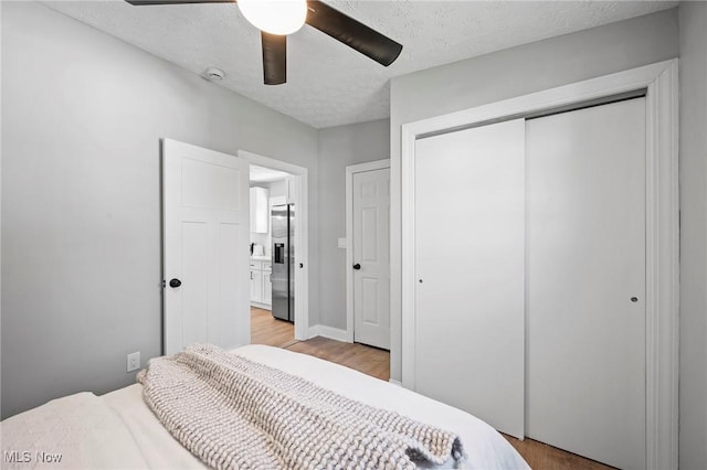 4394 W 139th St, Cleveland, OH 44135 - bedroom with a closet, a textured ceiling, stainless steel fridge with ice dispenser, a ceiling fan, and light wood finished floors