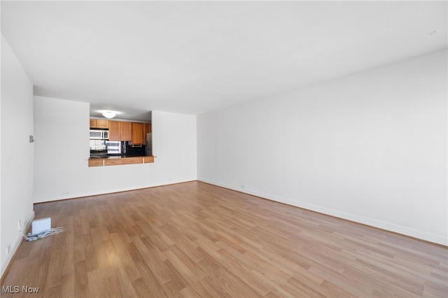 unfurnished living room with baseboards and light wood-style flooring