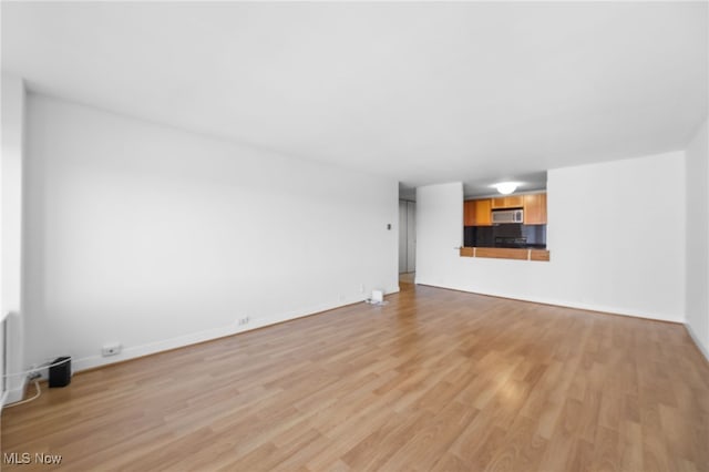 unfurnished living room featuring baseboards and light wood-type flooring