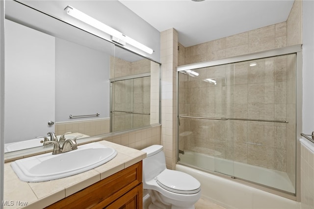 bathroom featuring vanity, combined bath / shower with glass door, and toilet