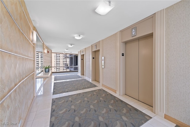 corridor featuring light tile patterned floors, elevator, and wallpapered walls