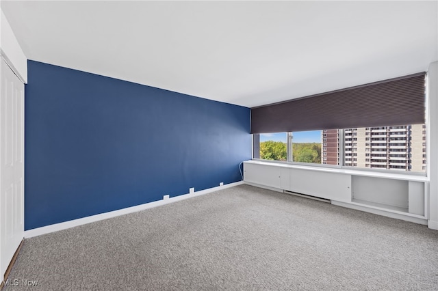 unfurnished room featuring carpet flooring, baseboards, and a baseboard heating unit