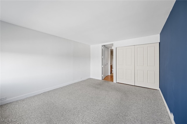 unfurnished bedroom featuring baseboards, carpet flooring, and a closet